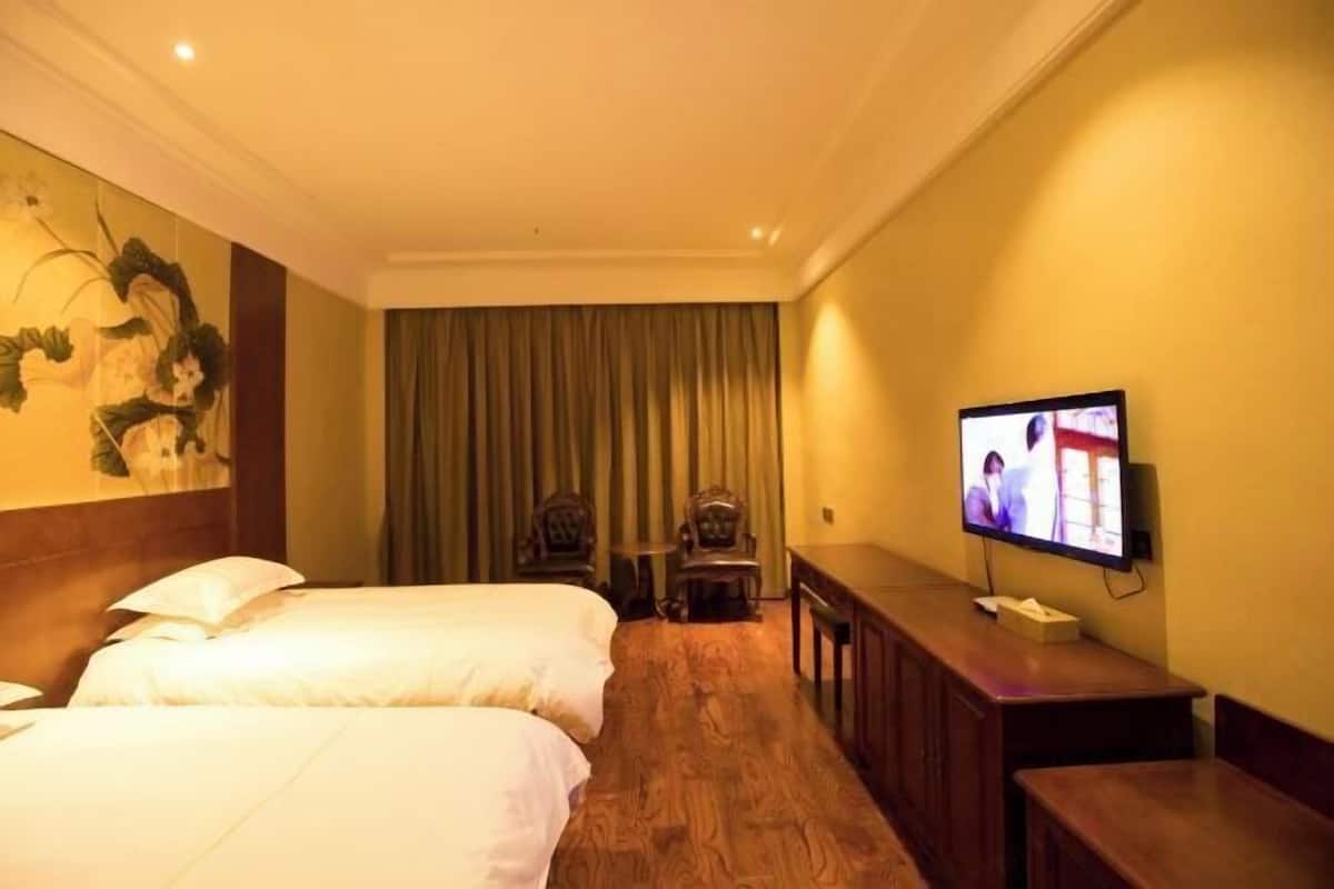 Une chambre d’hôtel avec deux lits, une télévision, un bureau et une chaise.