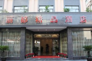 L’entrée d’un hôtel, avec un tapis rouge, de grandes fenêtres et des plantes en pot.