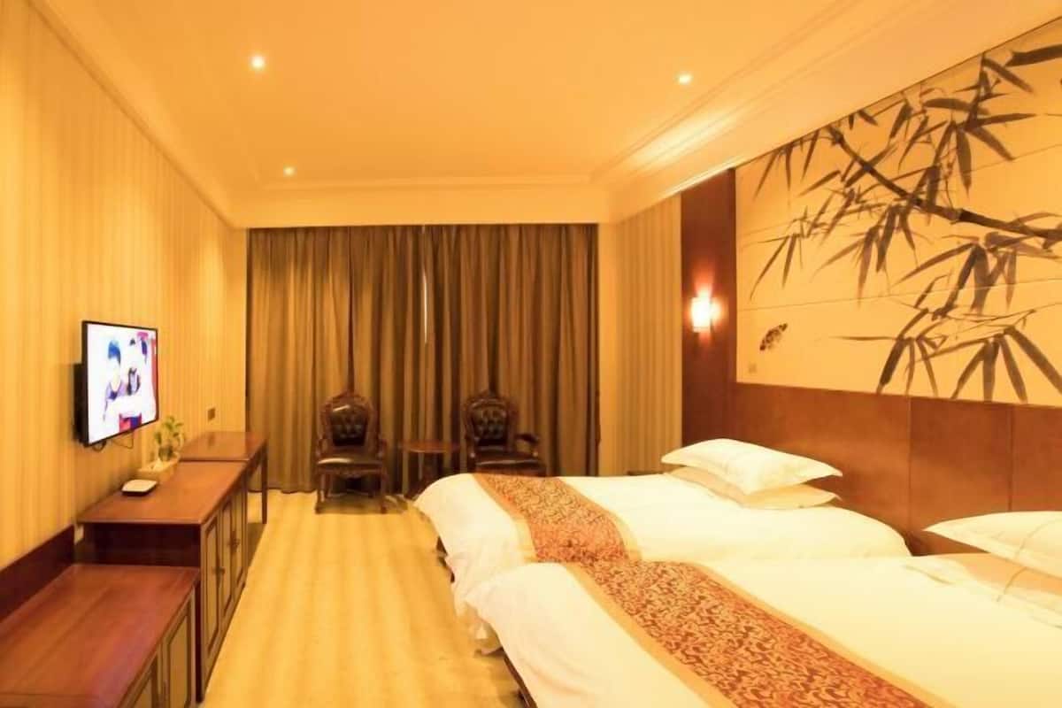 Une chambre d’hôtel avec un grand lit, une télévision, un bureau et un mur orné d’une œuvre d’art en bambou.