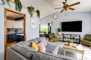 A living room with a sofa, a coffee table, a TV, and a ceiling fan.