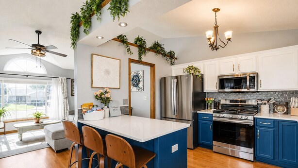 A modern kitchen with a central island, stainless steel appliances, blue cabinets, and a ceiling fan. - Prairie Peace - Family & Pet-Friendly Home on Quiet Cul-De-Sac w/ Games & Toys (Wichita)