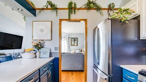 A compact kitchen with a central island, a built-in refrigerator, and a wooden ceiling with hanging plants. - Prairie Peace - Family & Pet-Friendly Home on Quiet Cul-De-Sac w/ Games & Toys (Wichita)