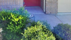A red front door with a window, a brick wall, and a garage door.