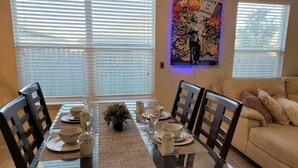 A dining area with a glass table set for four, surrounded by chairs.