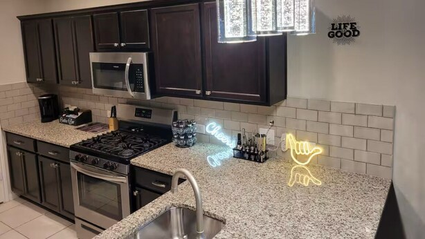 A modern kitchen with dark cabinets, stainless steel appliances, and a granite countertop.