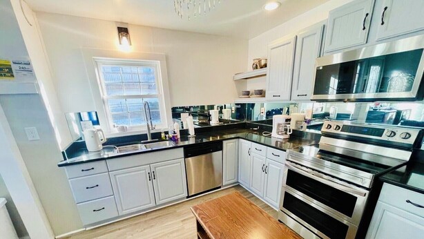 Una cocina moderna con electrodomésticos de acero inoxidable, armarios blancos y un banco de madera.