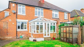 A brick house with a conservatory, a garden, and a wooden shed.