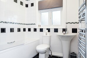 A modern bathroom with a white bathtub, toilet, and sink. - 4-Bed Retreat, Spacious Oasis with Modern Comfort (Southampton)