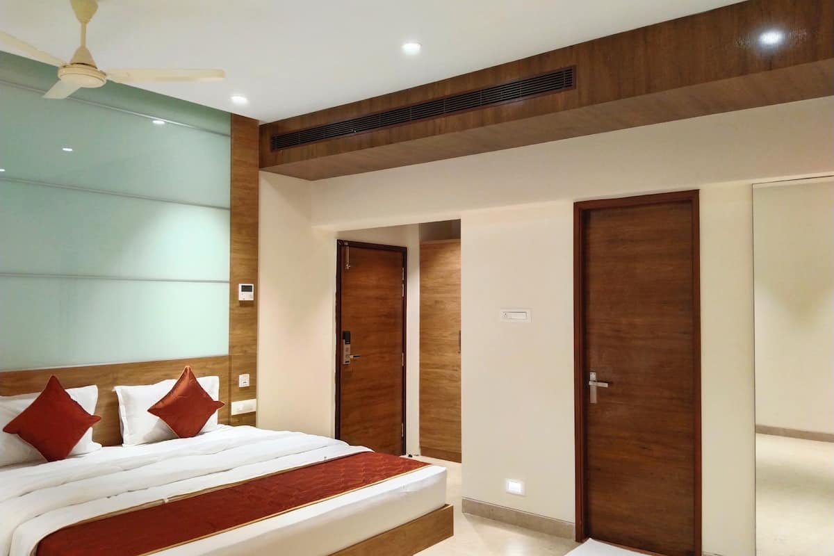 Ein Hotelzimmer mit Bett, Holz-Kopfteil, zwei Kleiderschränken, Deckenventilator und Einbauleuchten.