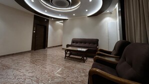 Un hall d’entrée spacieux avec un sol en marbre, un canapé et des fauteuils.