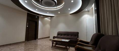 Un vestíbulo amplio con piso de mármol, un sofá y sillones.