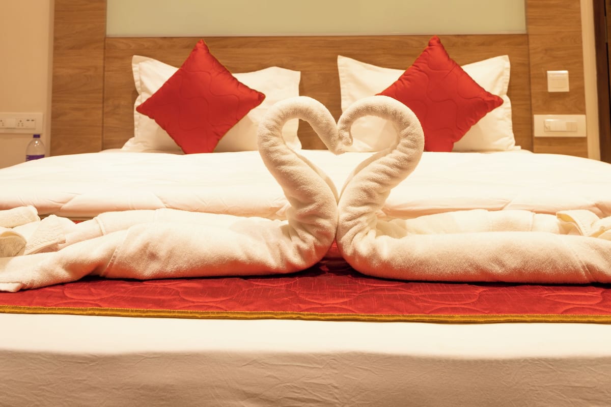 Ein Hotelzimmer mit einem großen Bett, roten Kissen und einer Handtuch-Herz-Arrangement.