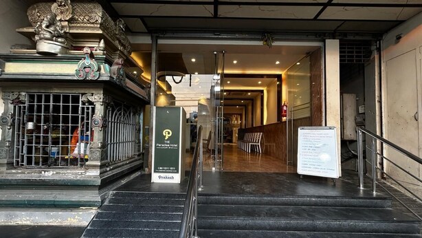 L’entrée d’un hôtel, avec un escalier menant au hall d’accueil, un comptoir de réception et un panneau indicateur.