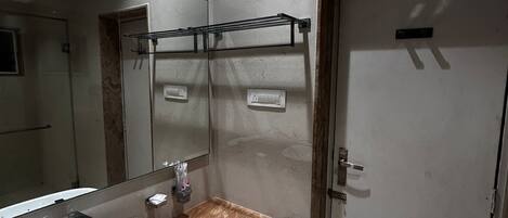 A modern bathroom with a large mirror, a white sink, and a door.