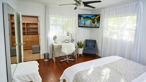 Ein Schlafzimmer mit Bett, Schreibtisch, Stuhl, Fernseher und Kleiderschrank.