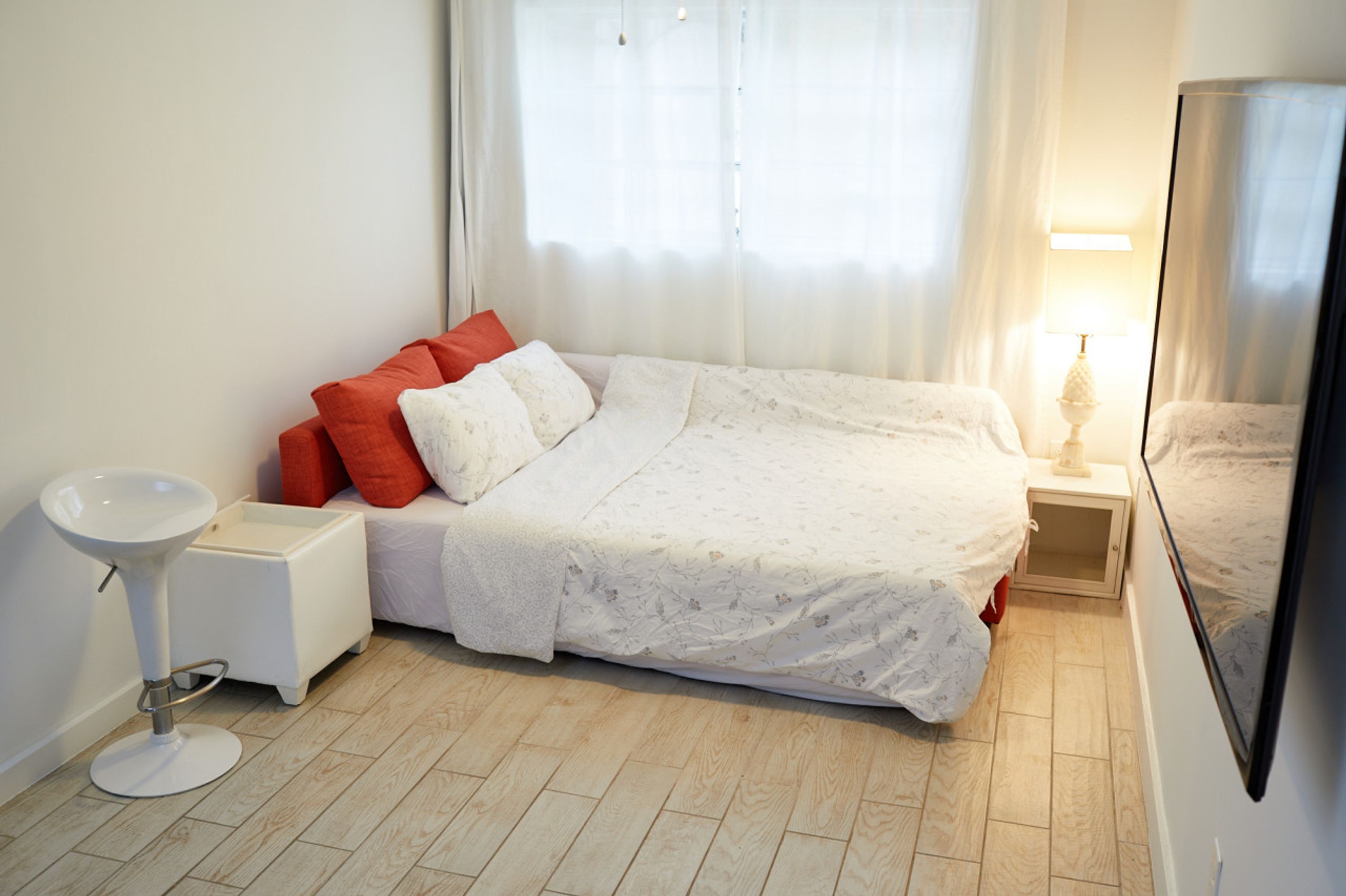 Une chambre à coucher avec un lit, une table de chevet, une lampe et un miroir.