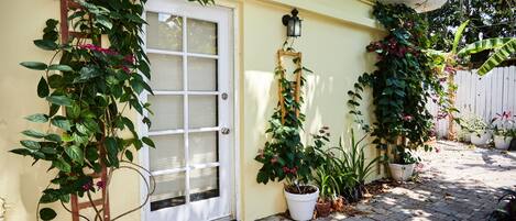A house with a white door, potted plants, and a wooden ladder leaning against the wall.