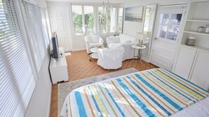 A bedroom with a bed, a white sofa, a small table, and a TV. - Miami Pool Cottage in El Portal (Miami)