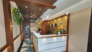 A reception desk with a modern design, a ceiling fan, and a decorative wall with framed pictures. - Hotel Prime Suites Airoli (Navi Mumbai)