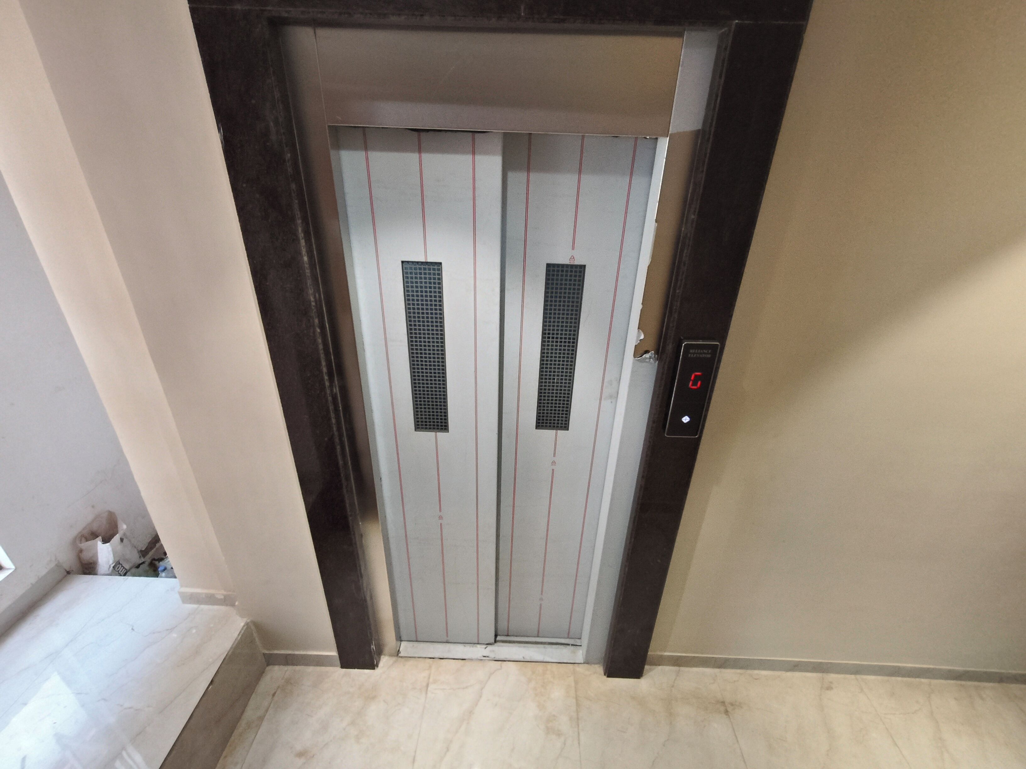 An elevator with a digital display, a vent, and a door with a handle.