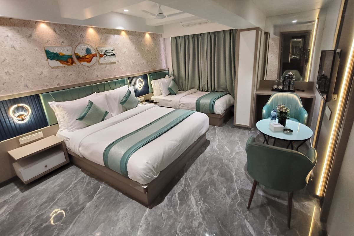 A hotel room with two beds, a small table, a chair, a mirror, and artwork on the wall.