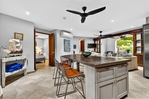 A modern kitchen with a central island, bar stools, and a ceiling fan. - Beach Villa las Catalina’s (Las Catalinas)