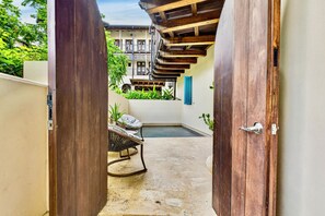 Ein schmaler Innenhof mit einer Holztür, einem Metallstuhl und einem kleinen Pool.