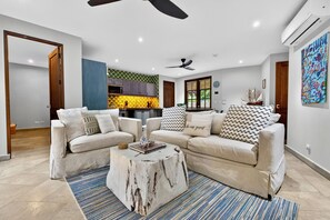 A living room with a sectional sofa, a coffee table, and a dining area with a kitchen in the background. - Beach Villa las Catalina’s (Las Catalinas)