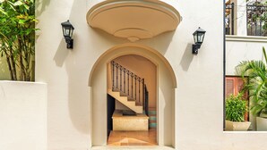 Una escalera conduce a un piso superior, flanqueada por dos faroles y un techo curvo.