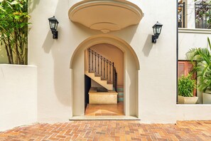 Eine Treppe führt zu einer oberen Etage, begleitet von zwei Wandleuchtern und einer gewölbten Decke.