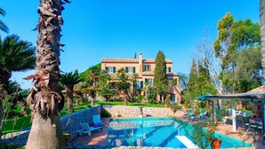 A large, multi-story building with a pool area, surrounded by palm trees and other greenery. - Villa la Cicaliera 10, Emma Villas (Sanremo)