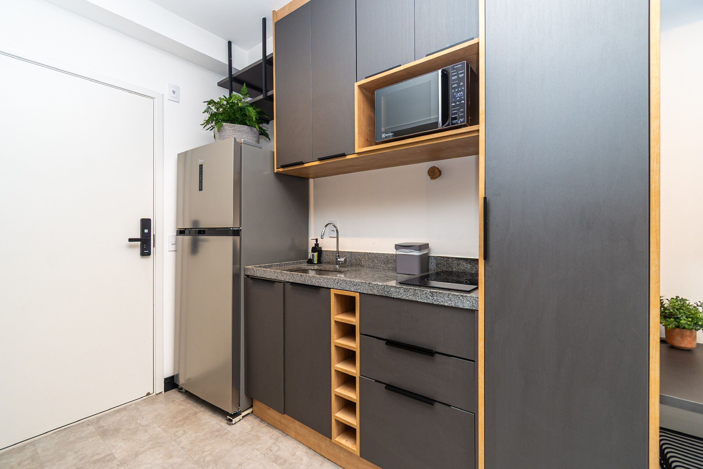 A compact kitchen with a built-in microwave, a stainless steel refrigerator, and a small sink.