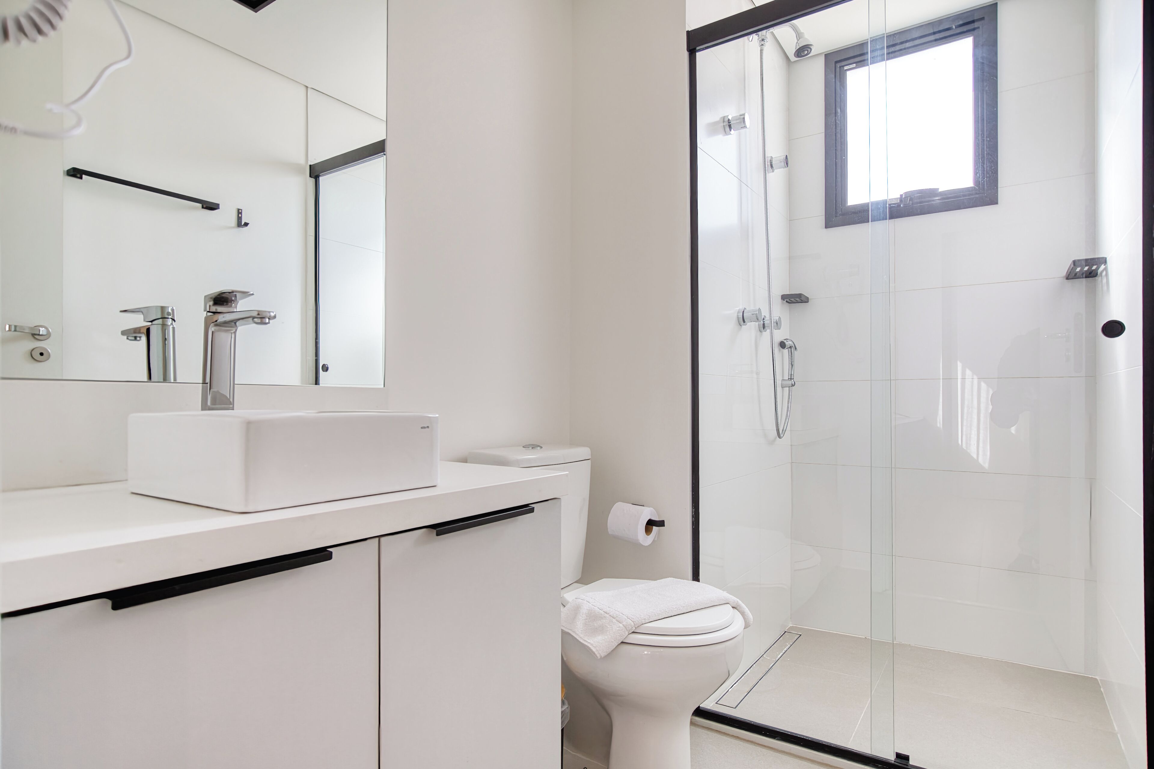 Un baño moderno con cabina de ducha de vidrio, un lavabo blanco y un inodoro.