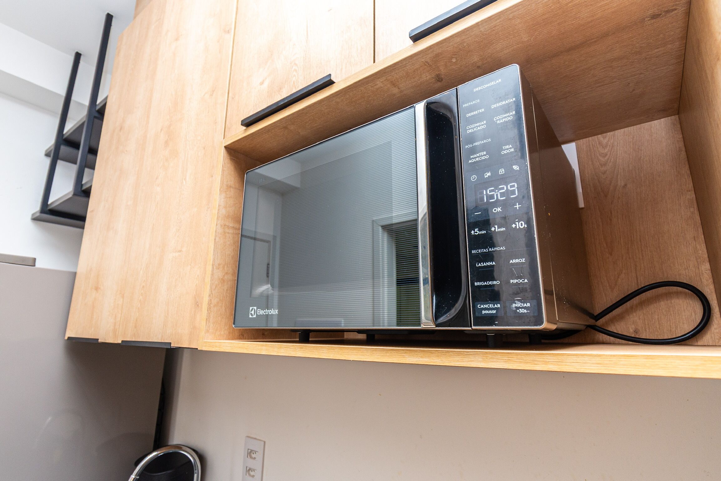 Un four à micro-ondes posé sur une étagère en bois dans une cuisine.