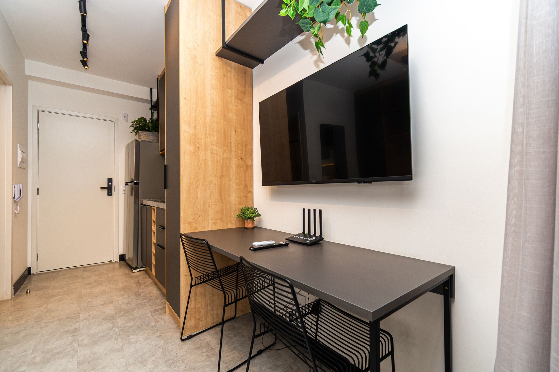 Une cuisine moderne équipée d’un téléviseur à écran plat, de deux chaises noires et d’un meuble en bois.