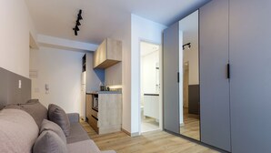 A modern living room with a grey sofa, a kitchen area with wooden cabinets, and a sliding wardrobe. - 360 DNA Paulistano (Sao Paulo)