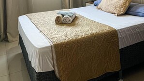 Habitación de hotel con cama, ventana con cortinas, aire acondicionado y mesita de noche con lámpara.