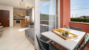 Een modern appartement met een eethoek, keuken en een balkon met een tafel en stoelen.