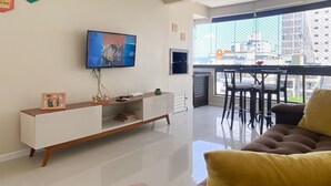 Un salon moderne avec un téléviseur à écran plat, un meuble de rangement blanc et un canapé.