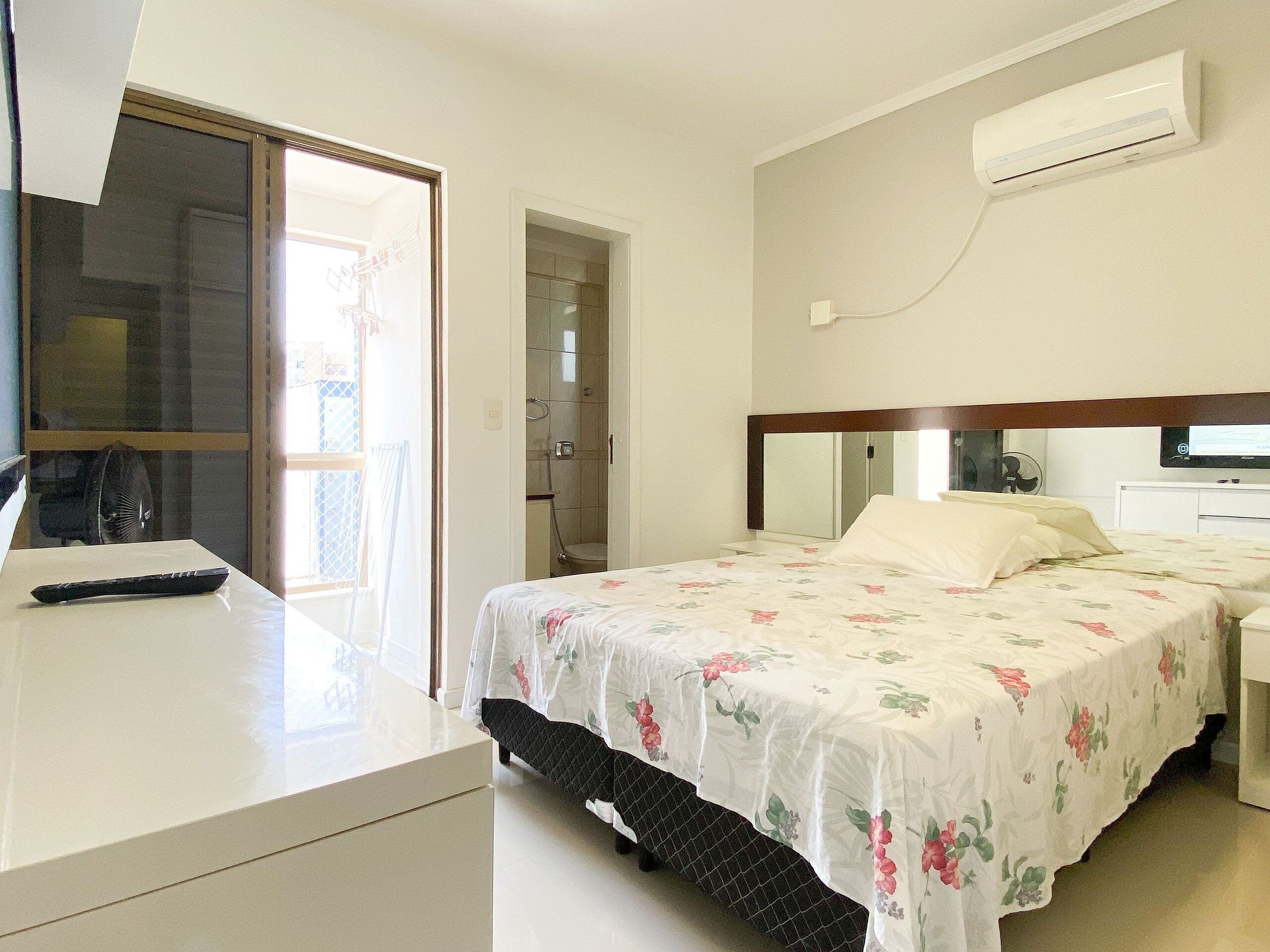 A bedroom with a bed, bedside table, and an air conditioning unit.