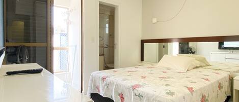 A bedroom with a bed, bedside table, and an air conditioning unit.