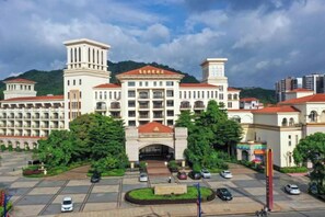 A large institutional building with multiple floors, a central entrance, and a parking area in front. - Fugang International Hotel (Pingyuan)