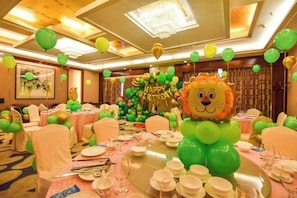 Un salón de banquetes con mesas redondas, sillas y una gran decoración con globos.