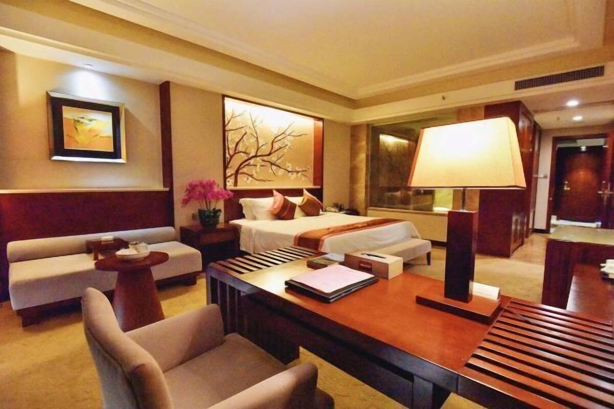 Une chambre d’hôtel avec un canapé, un lit, un bureau, une lampe et un tableau au mur.