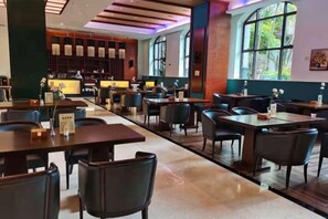 A spacious restaurant with multiple tables and chairs, a bar area, and large windows providing natural light. - Fugang International Hotel (Pingyuan)