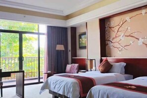 Habitación de hotel con dos camas, un ventanal grande, un balcón y un mural en la pared.