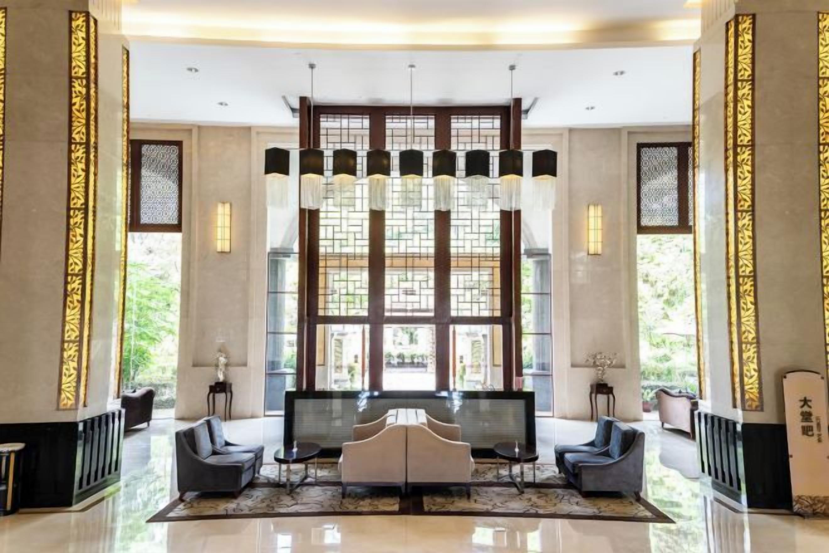 A spacious lobby with a large seating area, a reception desk, and a large window with decorative glass panels.