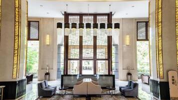 A spacious lobby with a large seating area, a reception desk, and a large window with decorative glass panels.