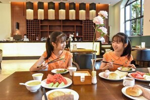 A restaurant setting with a wooden table, plates of food, and a vase with flowers. - Fugang International Hotel (Pingyuan)