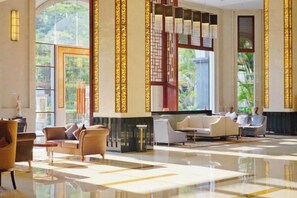 A spacious lobby with a high ceiling, large windows, and a seating area with sofas and armchairs. - Fugang International Hotel (Pingyuan)